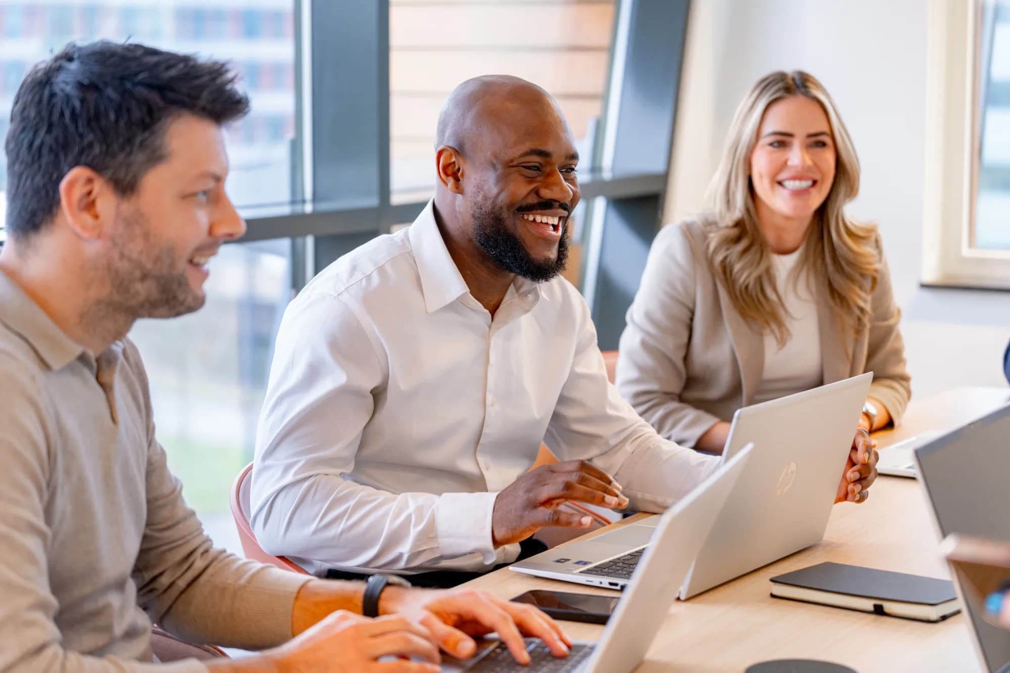 Drie personen in meeting op kantoor, samenwerken aan strategie en HR-planning.