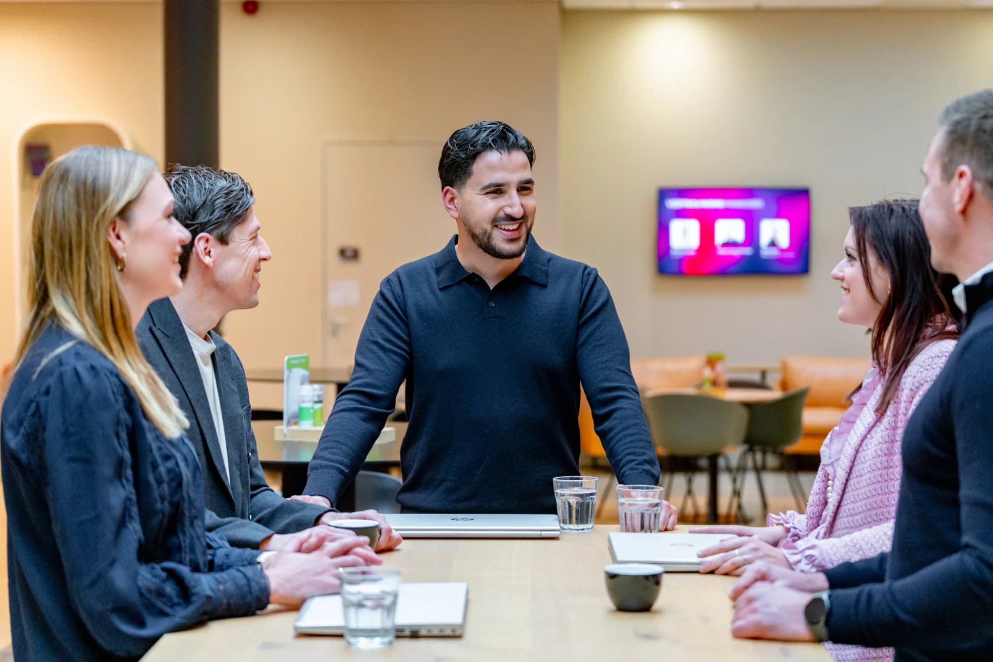 5 collega's lachend in een werkoverleg