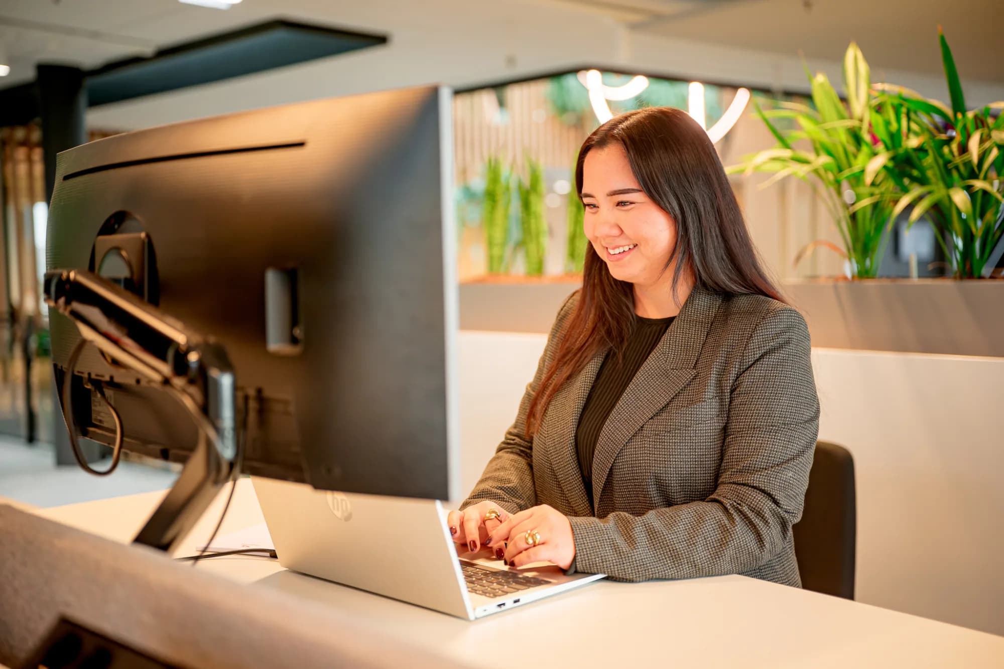 Lachende vrouw achter laptop / zorgvuldige start inhuurraamovereenkomst